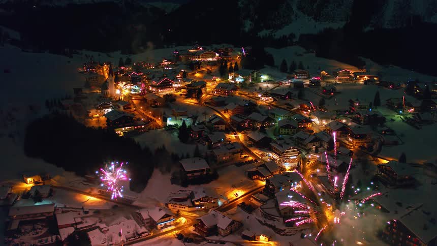Fireworks explode over a small village outside at night