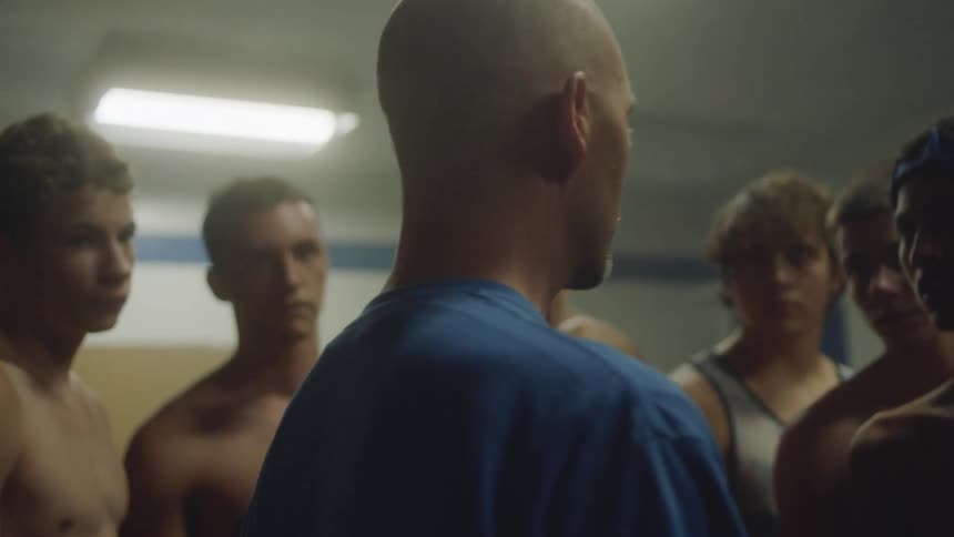 A group of young men huddle and speak