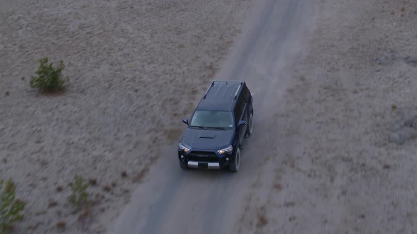 A vehicle drives on a rural dirt road