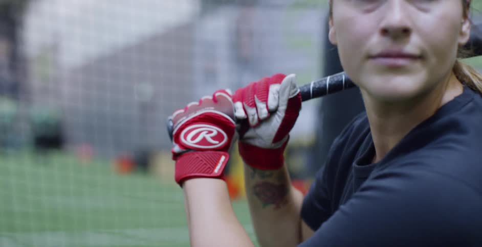 A woman holds a bat in a batting cage