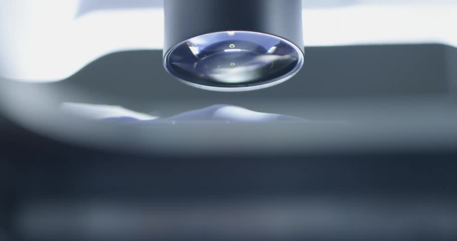 A glass slide is placed beneath a microscope