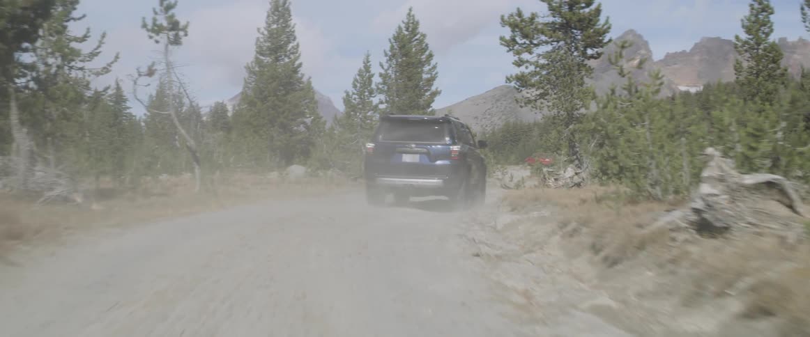 A truck drives on a dirt mountain road