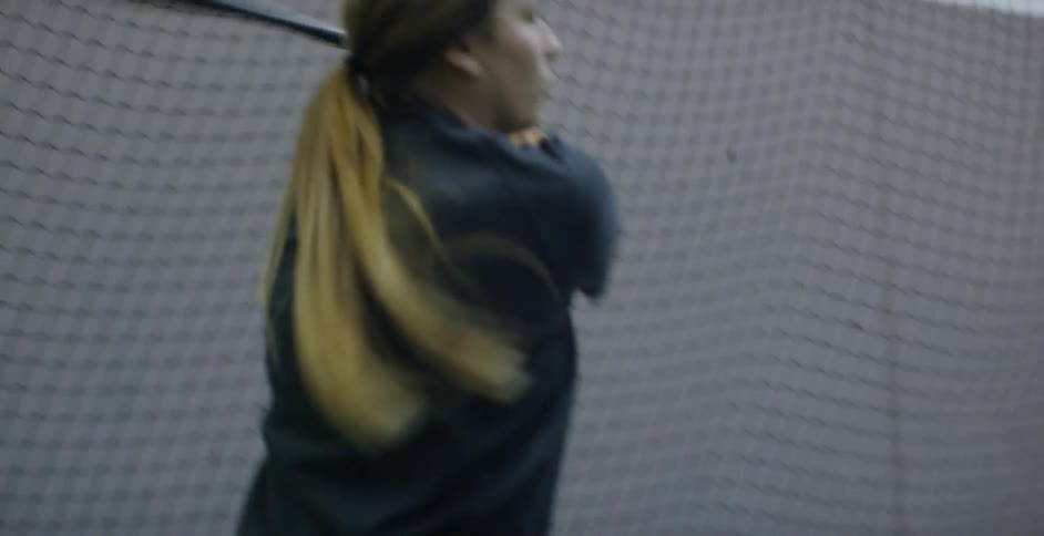 Woman swings a baseball bat in an indoor gym