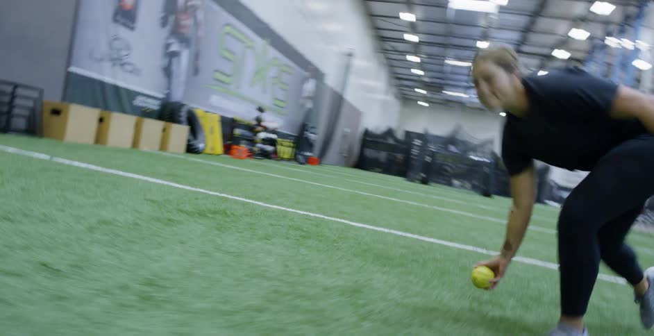 Woman runs to catch a yellow ball picks it up and throws it