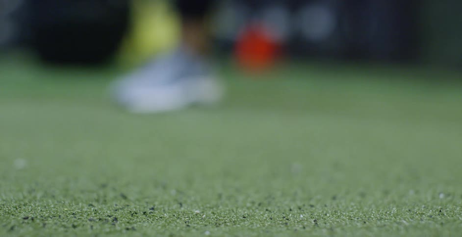 Person taps baseball bat on astroturf