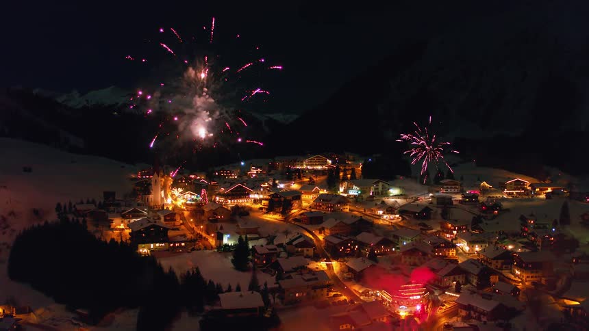Fireworks explode over a small village outside at night