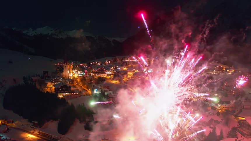 Fireworks explode above a snowy mountain village