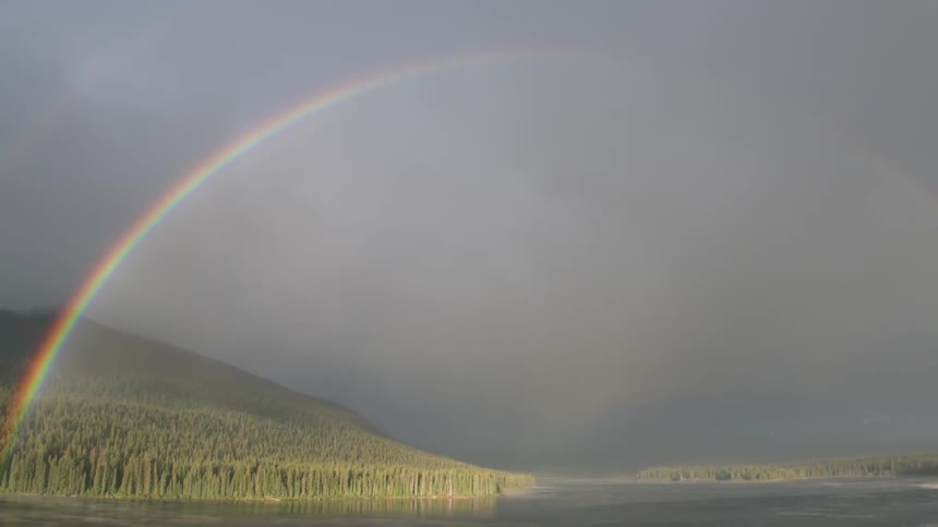 A full rainbow appearing to cross a lake
