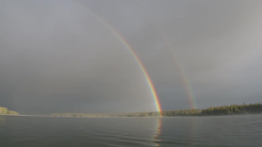 Rainbow shines over a lake on a cloudy day