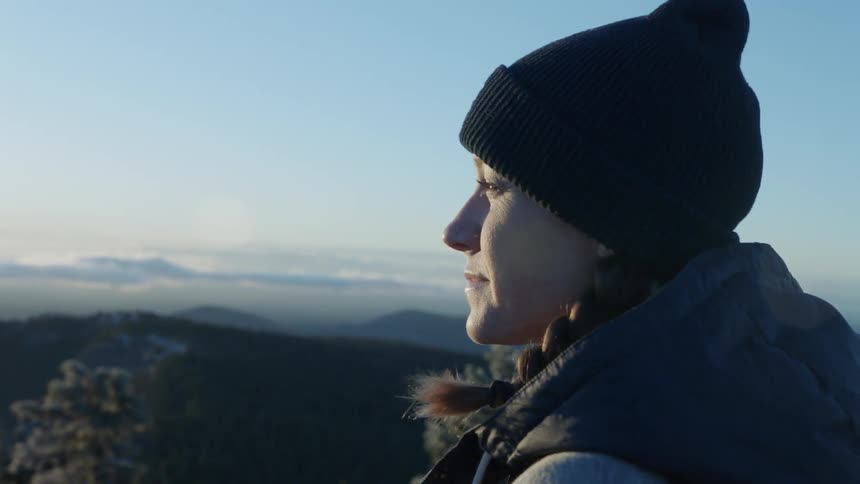 Woman wearing a toque looks out at the  mountains