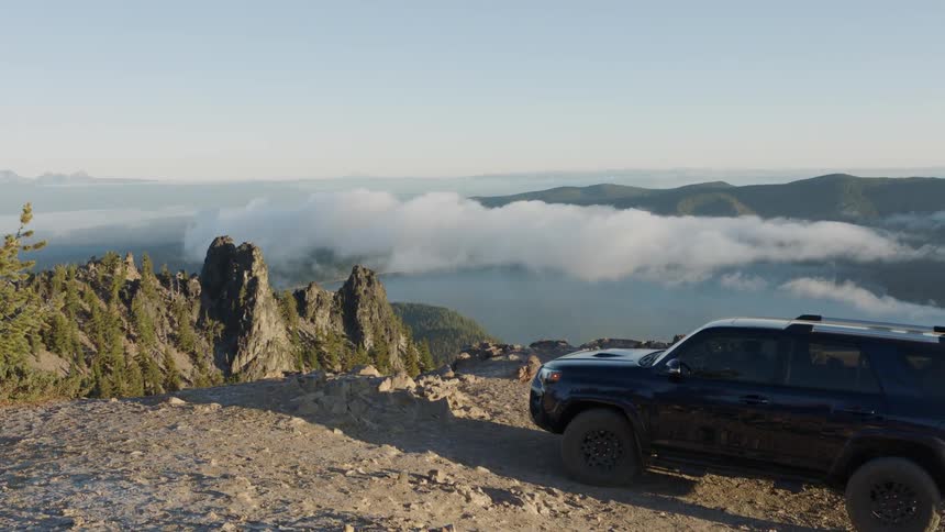 A vehicle parks on a dirt road in the mountains