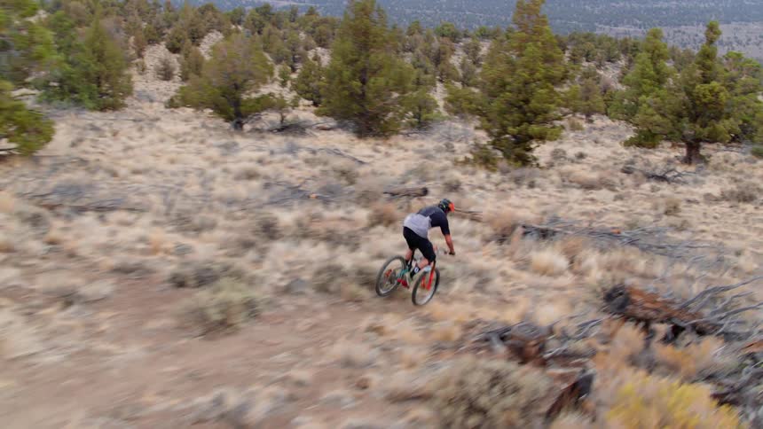 A man is riding a mountain bike on a dirt trail during the day