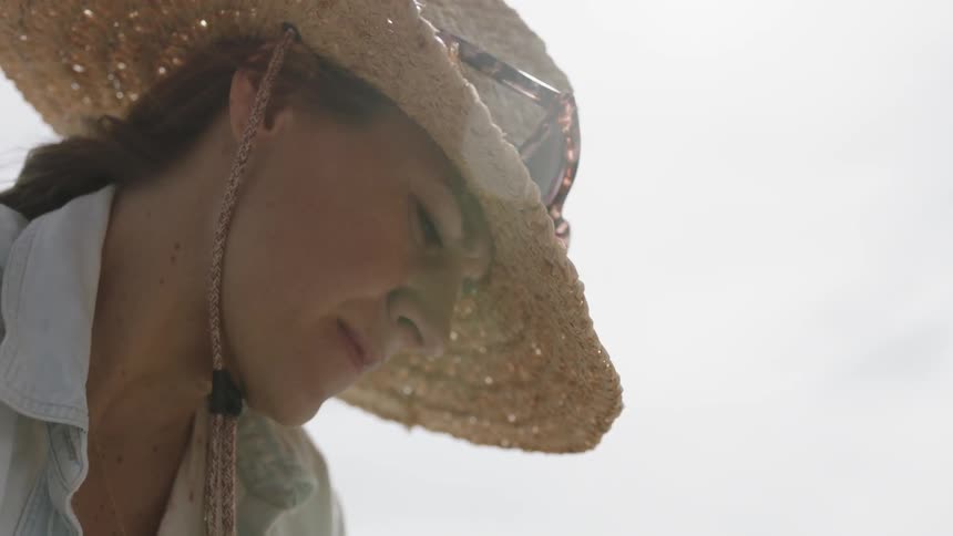 A woman wears a straw hat under the sun