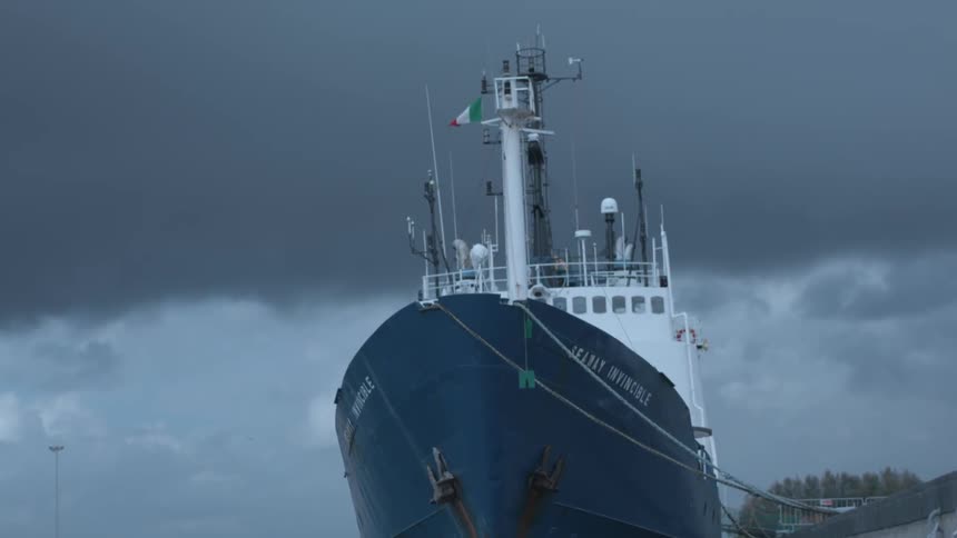 A commercial vessel is sitting docked in port on a stormy day