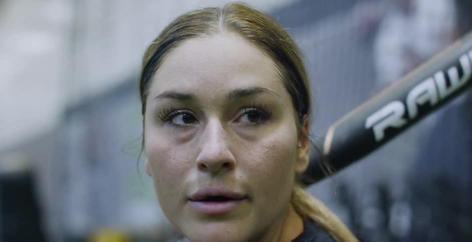 A woman softball player prepares to hit the ball