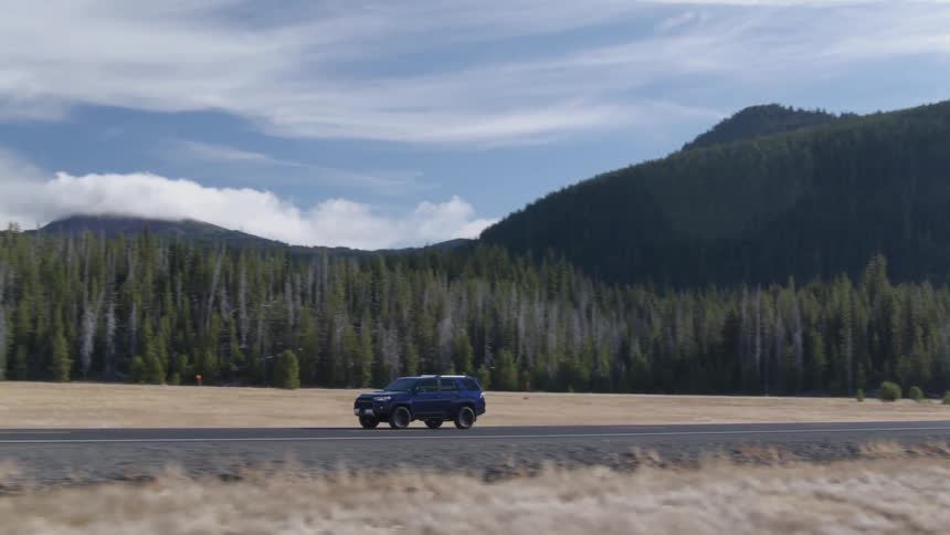 Car drives on a country road surrounded by mountains