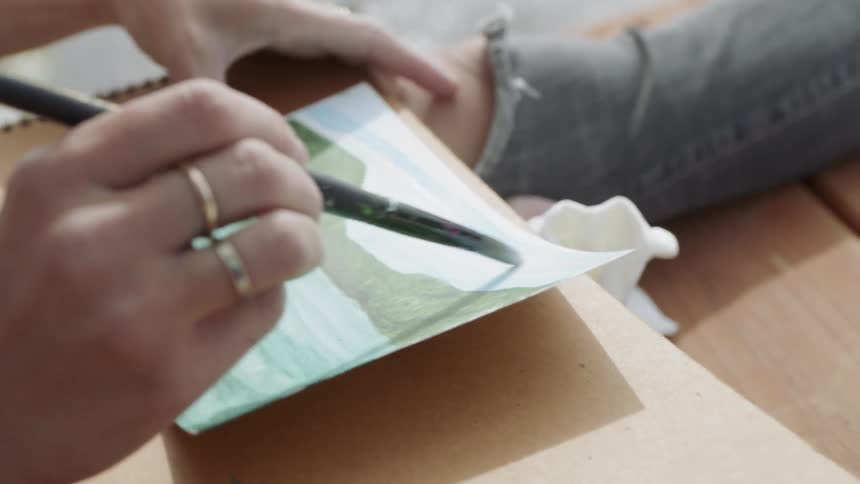 An artist paints on a lake dock
