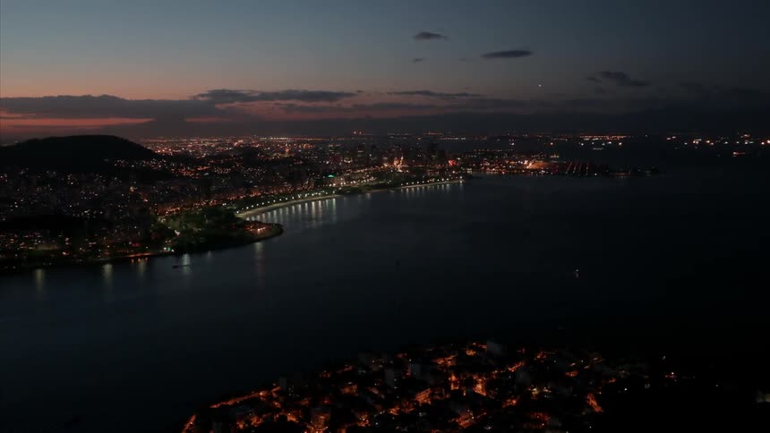 Traffic moves over bridges and coastal roads in a city at sunset