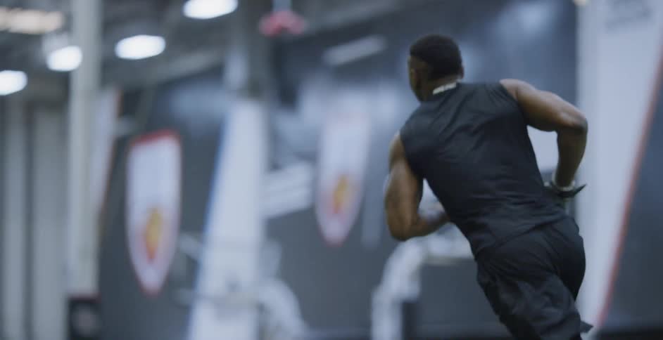A male athlete is catching a football as he trains indoors