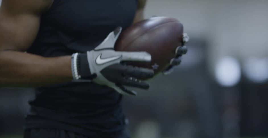 Man rotates a football in his gloved hands