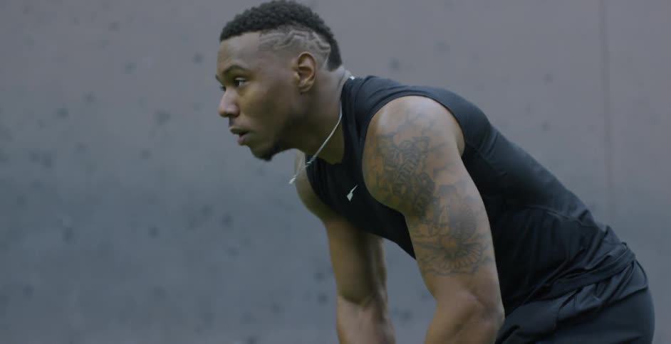 A male athlete is setting into position as he trains on an indoor football field