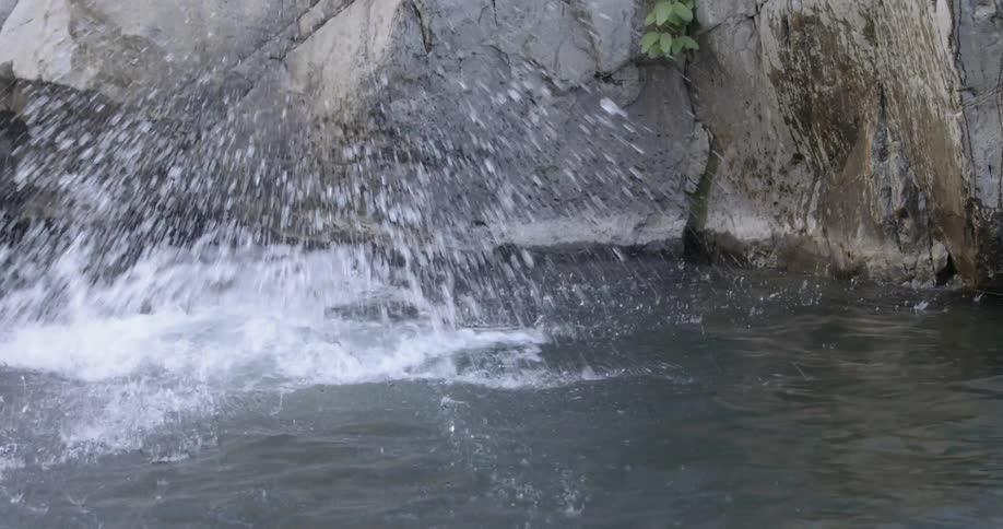 A man is free climbing up a rock face and falls into water