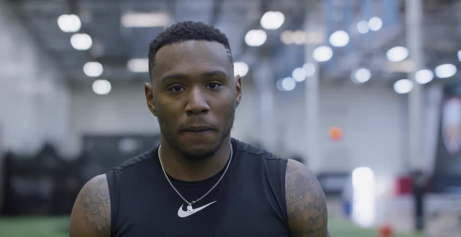 A male athlete is standing deep in thought indoors as he trains