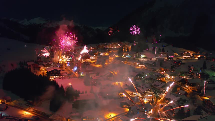 Many fireworks go off simultaneously in a snow covered town at night