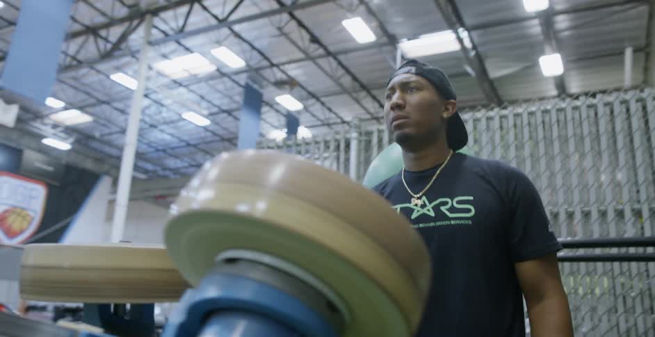 A man is shouting encouragement as he operates a football machine indoors