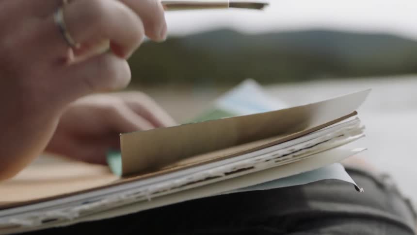 A woman paints on a small canvas outdoors