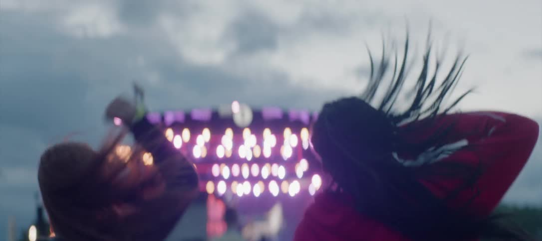 Concertgoers jump up and down at an outdoor venue