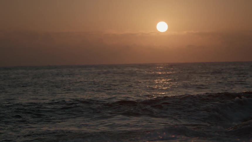 Waves coming ashore on a beach on a cloudy day at sunset