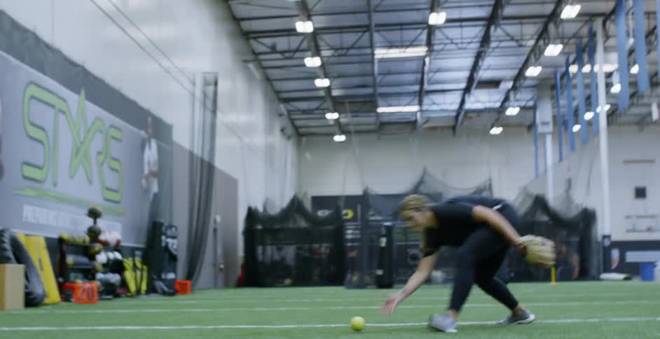 A woman plays softball on an indoor field