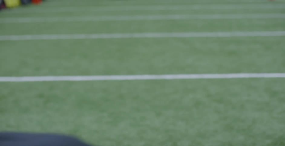 A male athlete is sprinting on an indoor football field