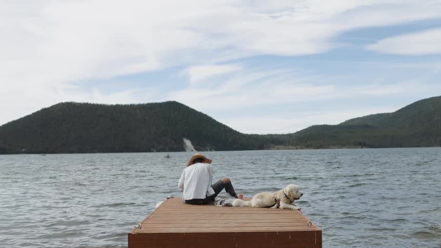 Woman sits on a dock with a dog