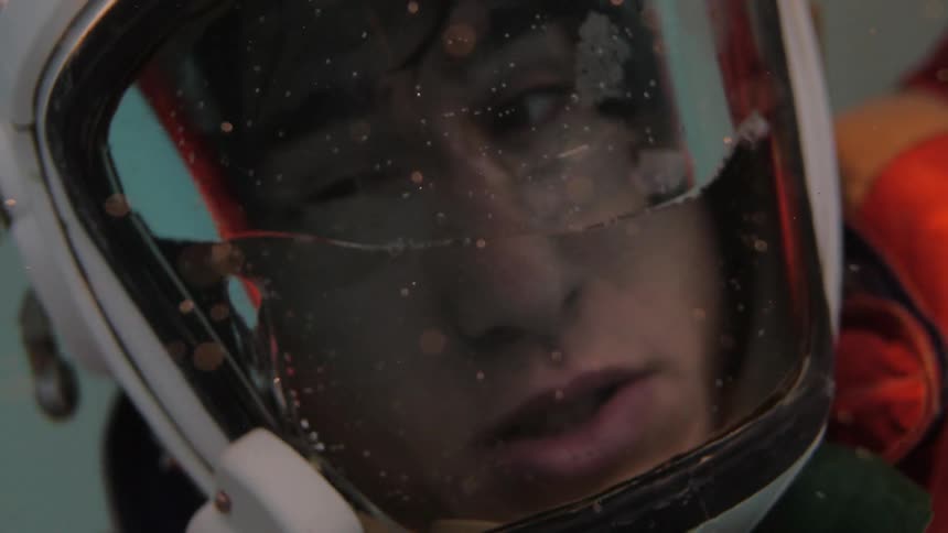 A man in an astronaut suit struggles underwater