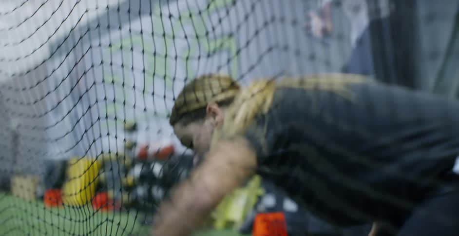 A woman softball player enters through nets