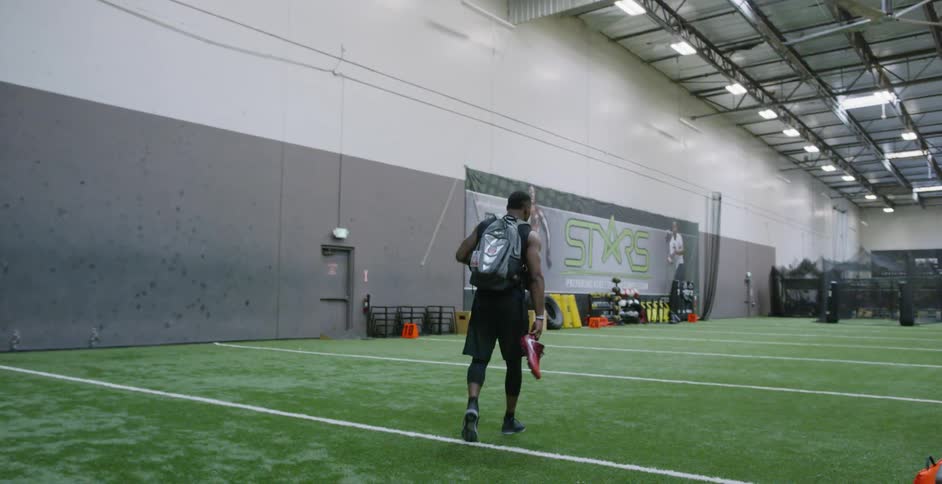 An athlete carries equipment on a training field
