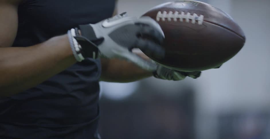 An athlete holds a football and smiles