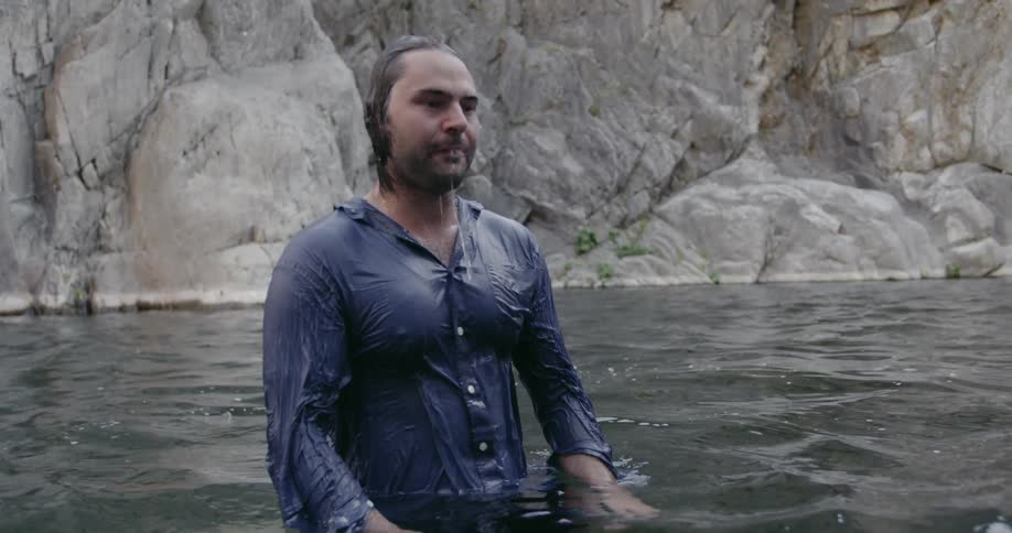 Man with wet clothes stands in the water