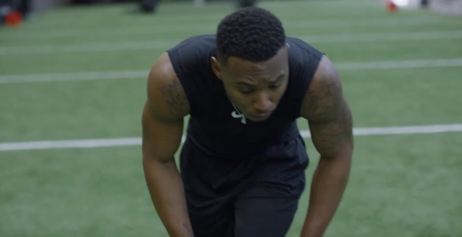 A male athlete is setting into position as he trains on an indoor football field