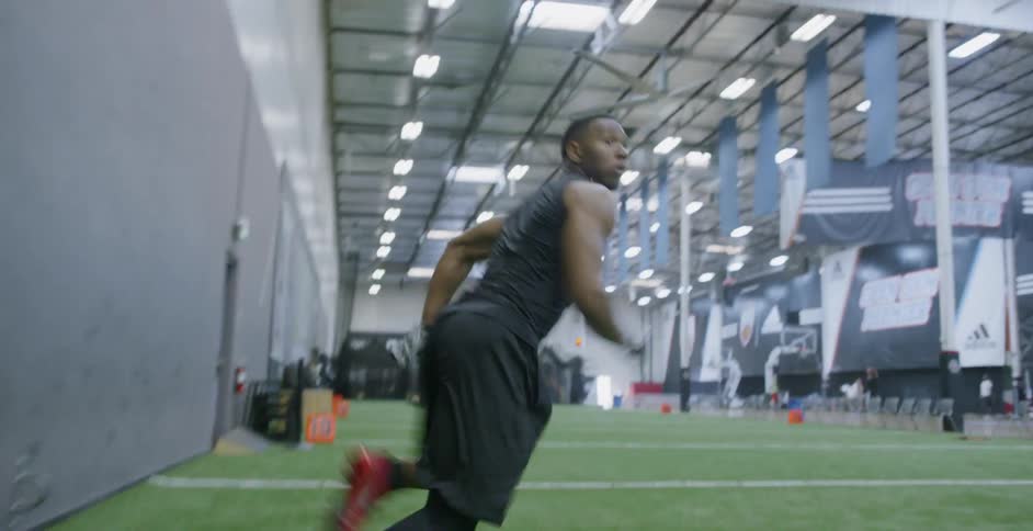 A male athlete is catching a football as he trains indoors