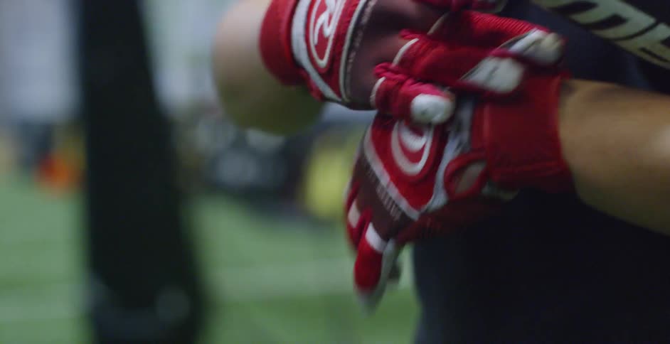 A baseball player puts on gloves and holds a bat