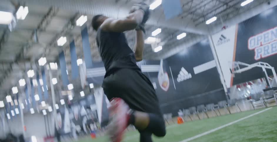 A male athlete is catching a football as he trains indoors