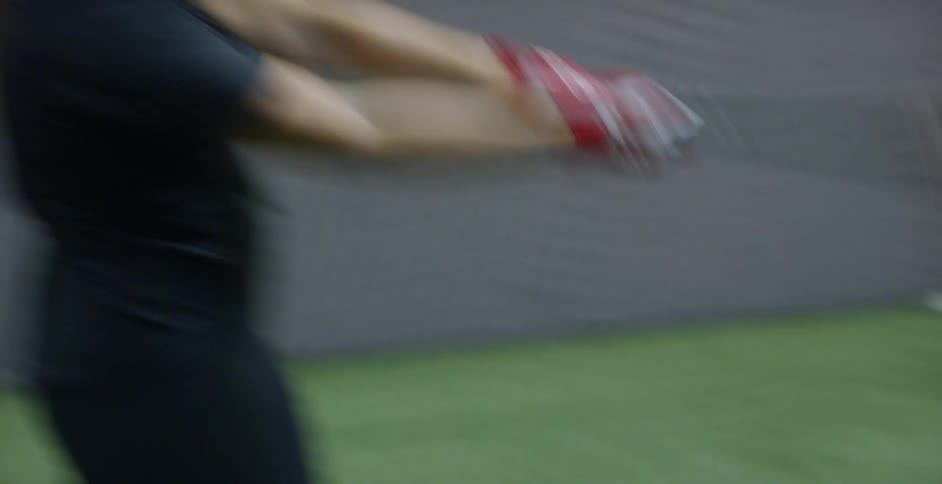 A woman softball player hits the ball indoors