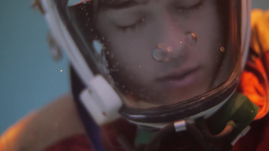 Person underwater as water fills helmet only opening his eyes when the water reaches the top