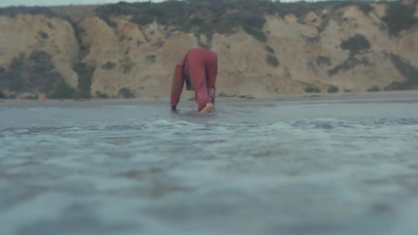 Man crawls out of the water towards the sand