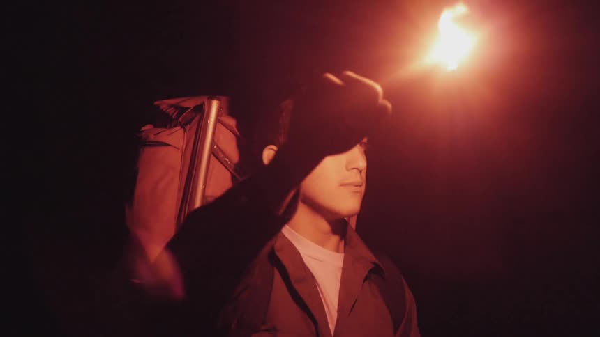 A hiker holds a flare in the dark