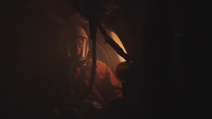 Man wearing a protective helmet sitting in a small dark area