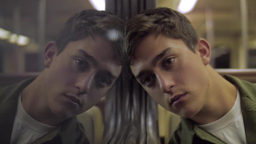 A man leans against a train window